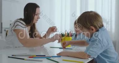 两个男孩的孩子和他的母亲坐在厨房里<strong>画画</strong>。 家庭幸福。 兄弟们在桌子旁<strong>画画</strong>。 实际